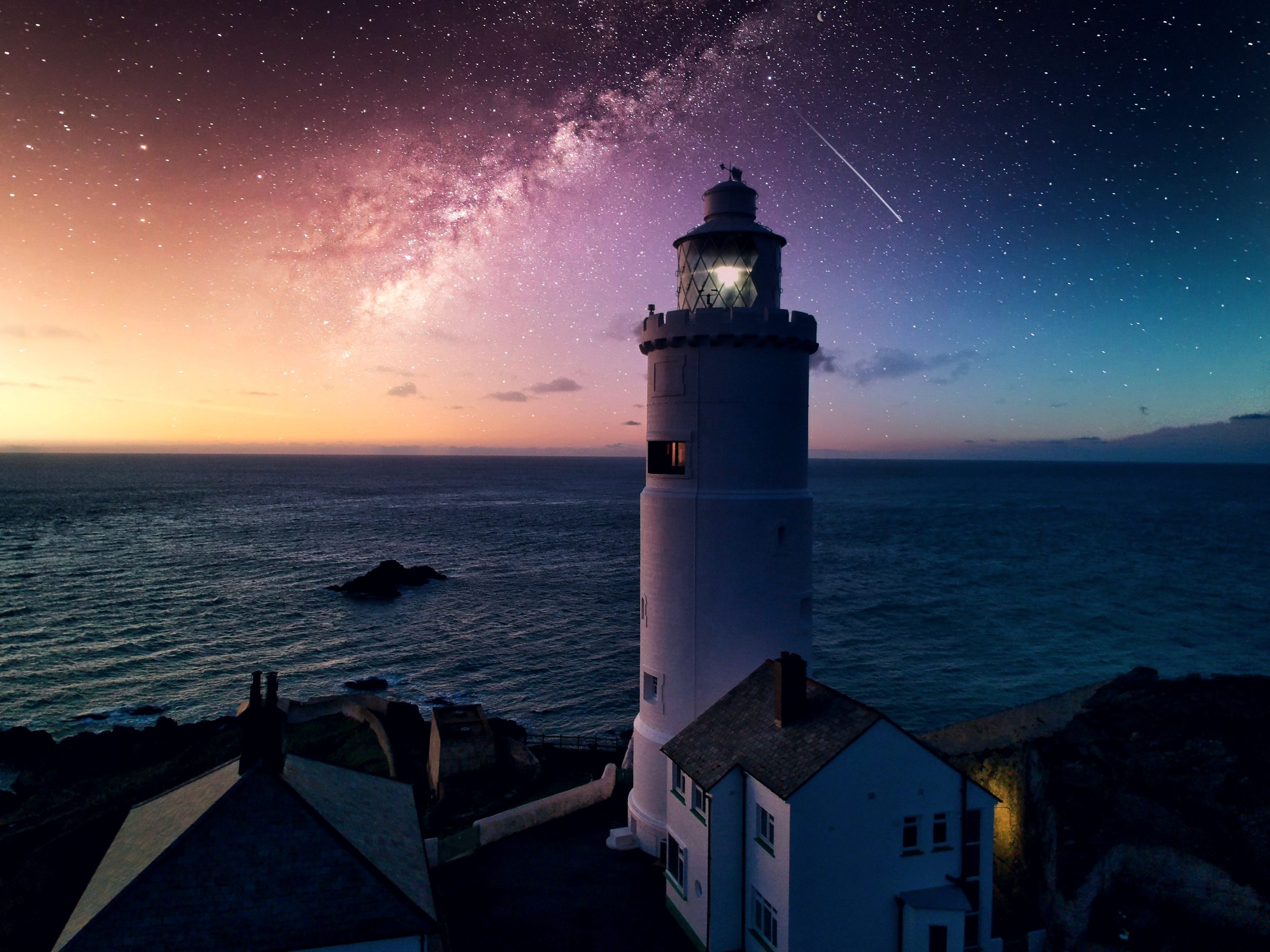 Lighthouse on a rocky coast under a night sky