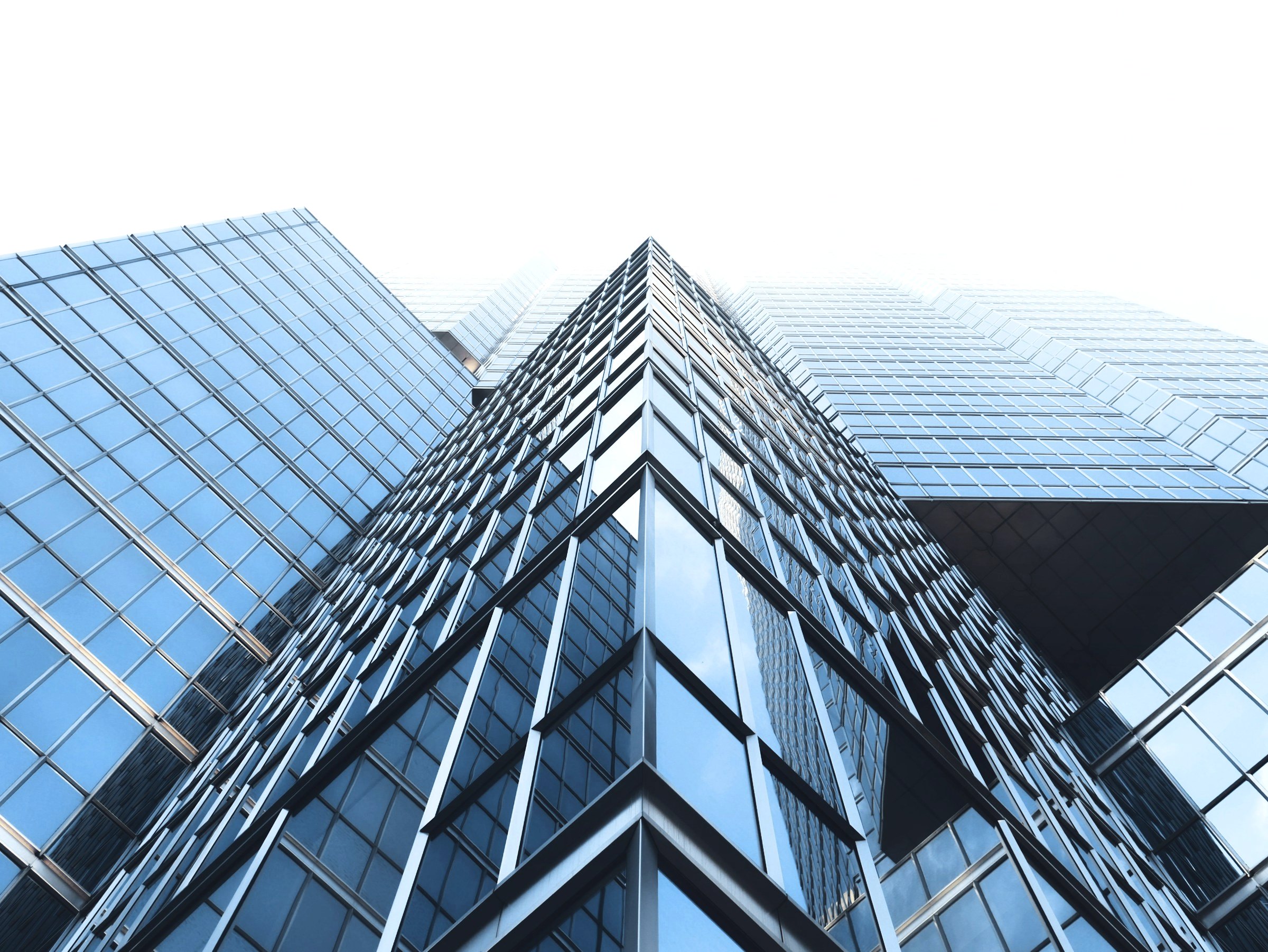 Glass office towers seen from below against a blue sky